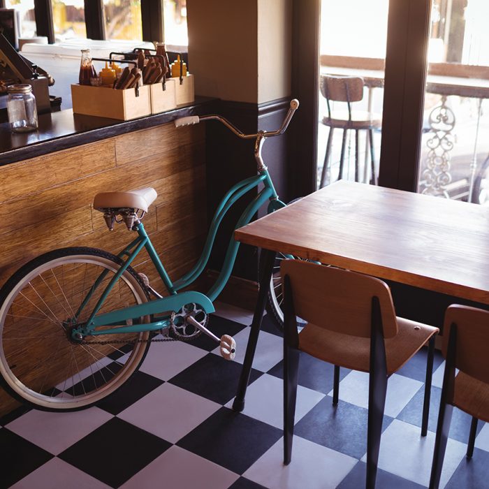Bicycle with empty table and chairs near counter in restaurant