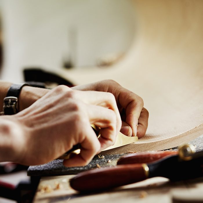 A furniture workshop making bespoke contemporary furniture pieces using traditional skills in modern design. A man working on a piece of curved wood.