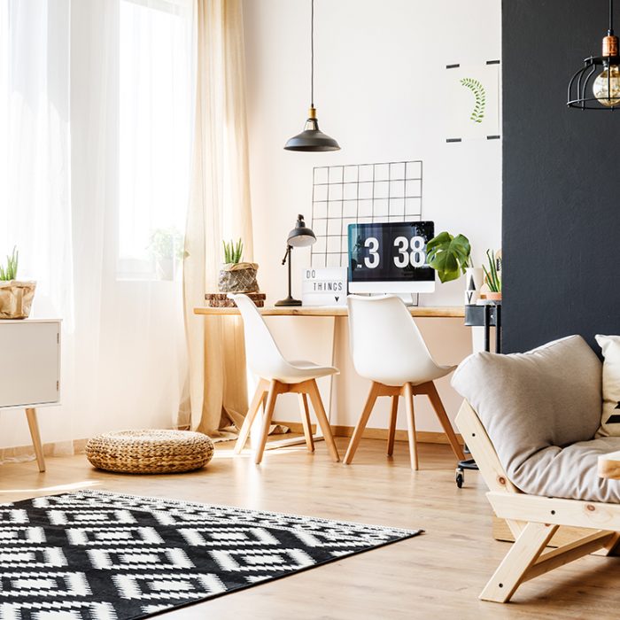 Spacious bright room with patterned carpet, black wall, sofa and workspace with scandinavian furniture