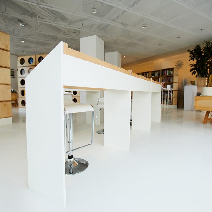 White angled tables and modern high chairs placed in center of bookstore room, creative bookcases in background